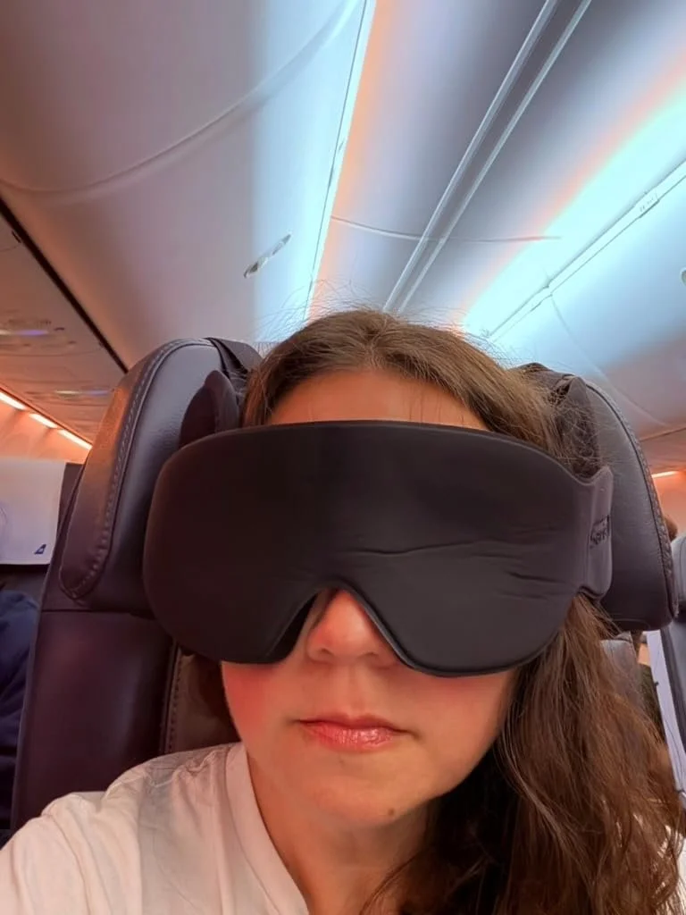 Traveler resting on an airplane seat with black travel comfort gear during a flight