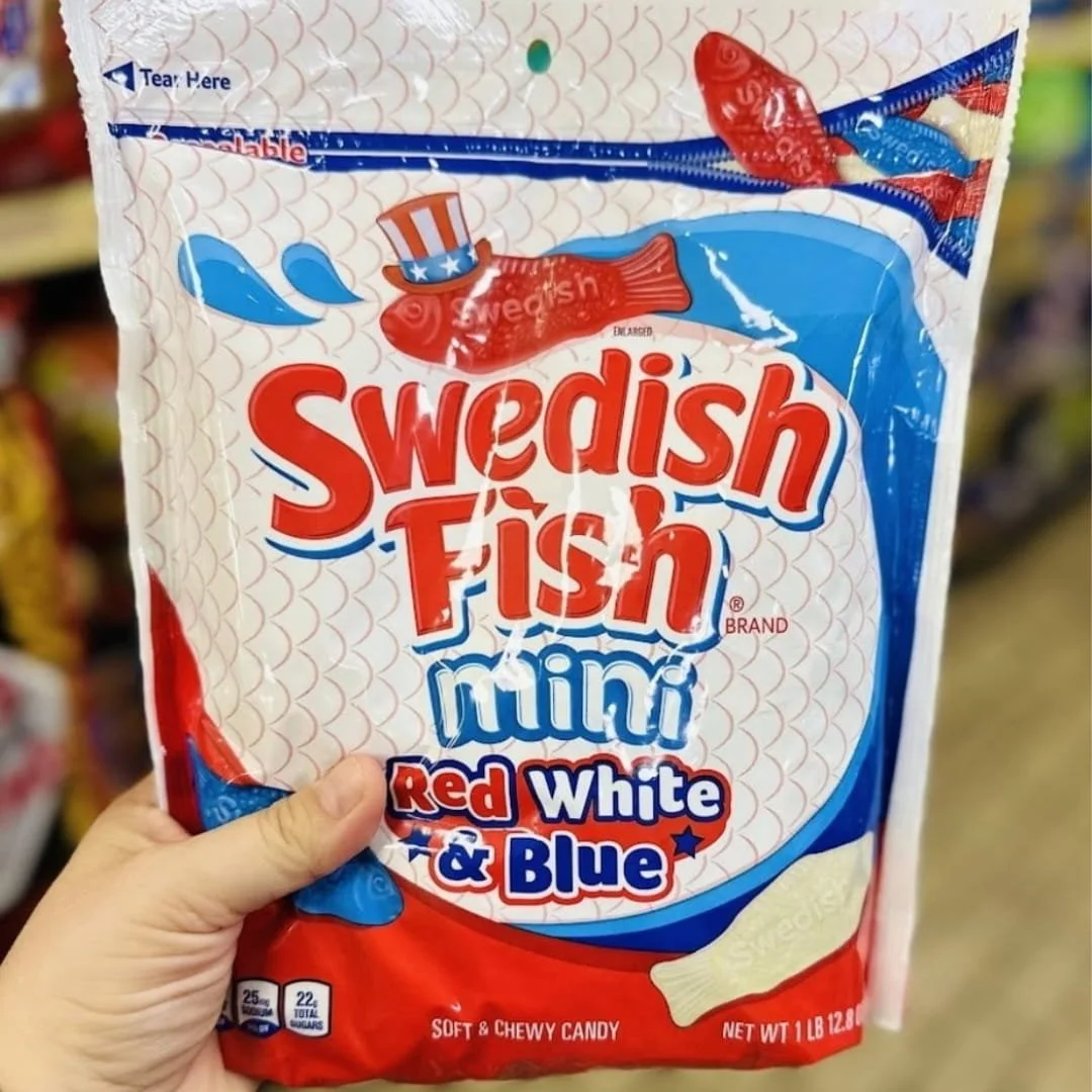 Bag of Swedish Fish Mini Red White and Blue soft chewy candy with patriotic red, white, and blue packaging held in a store aisle