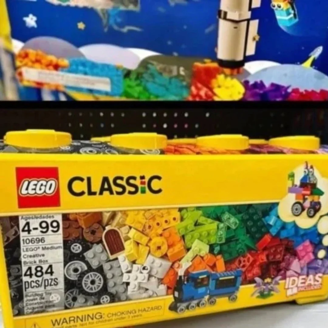 LEGO Classic Medium Creative Brick Box (set 10696) with 484 colorful pieces, including bricks, wheels, and tiles, displayed in a bright yellow box with a clear window and a space-themed background.
