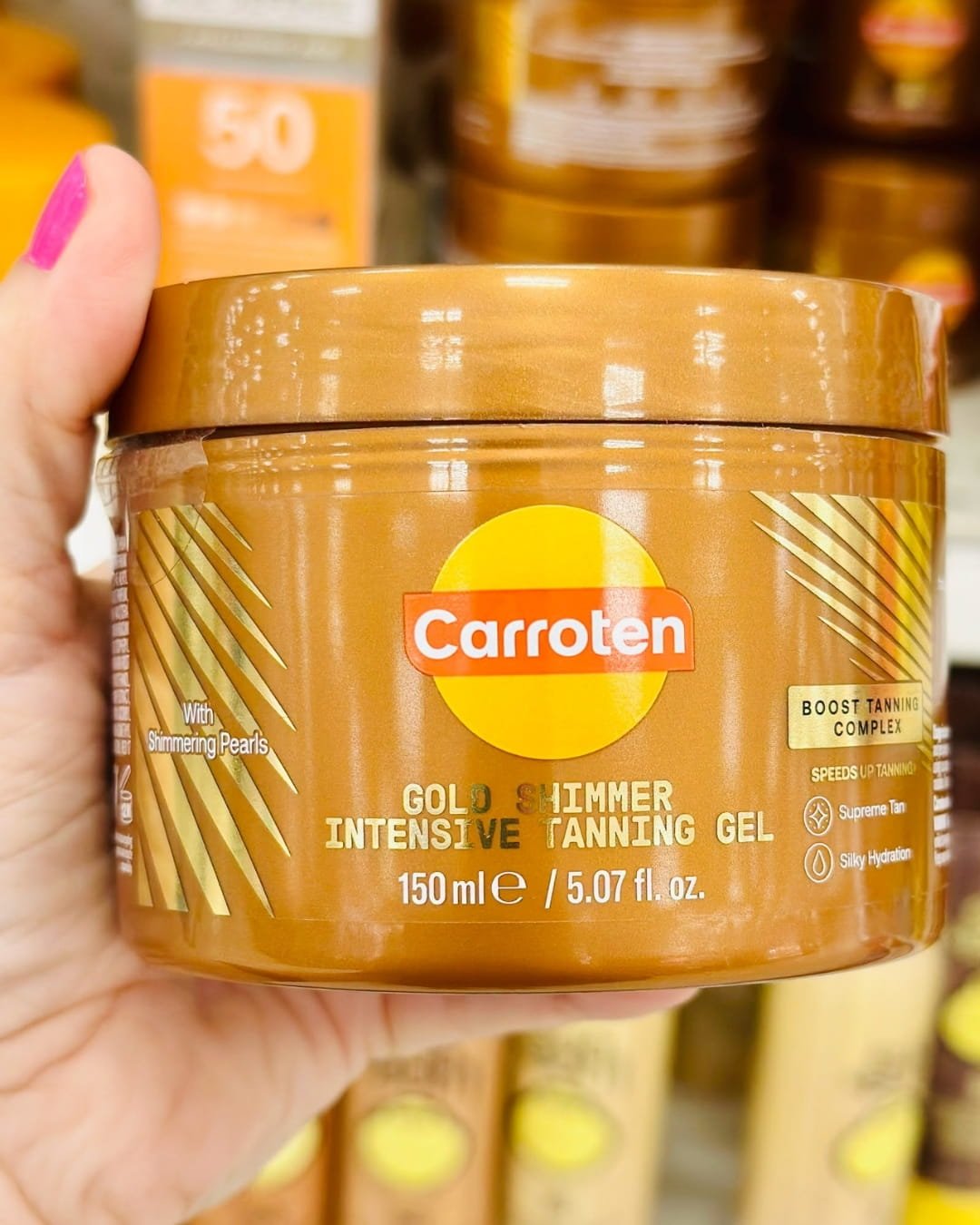 Carroten Gold Shimmer Intensive Tanning Gel tub held in hand in store aisle