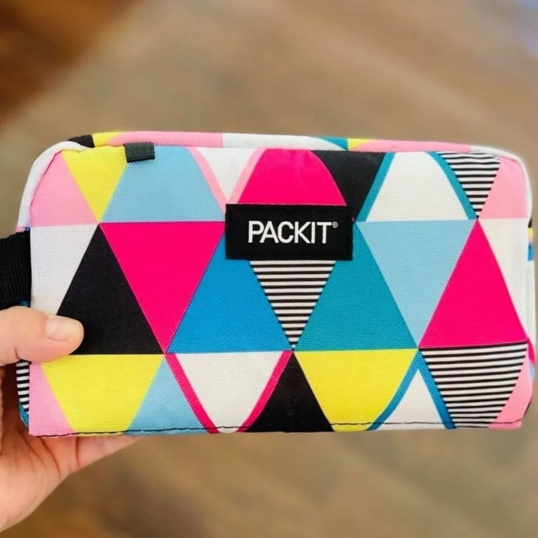 PackIt freezable snack box with colorful geometric pattern and black logo patch held in hand