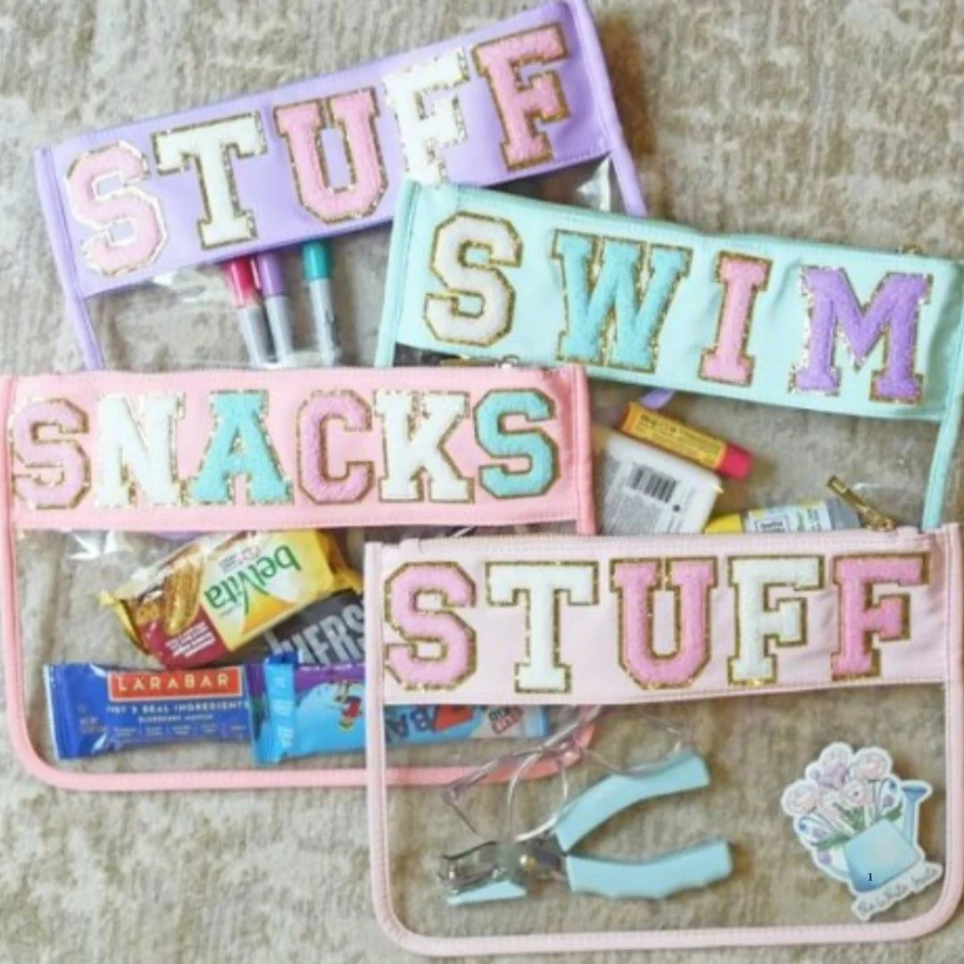 Stylish clear organizer pouches with pastel borders and chenille varsity letters, filled with everyday essentials like snacks and markers.