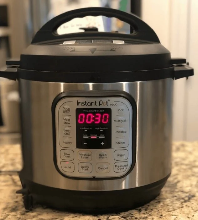 Instant Pot DUO electric pressure cooker with stainless steel body, digital timer displaying 00:30, and multi-function control panel featuring cooking presets like soup, rice, and yogurt, ideal for versatile kitchen use.
