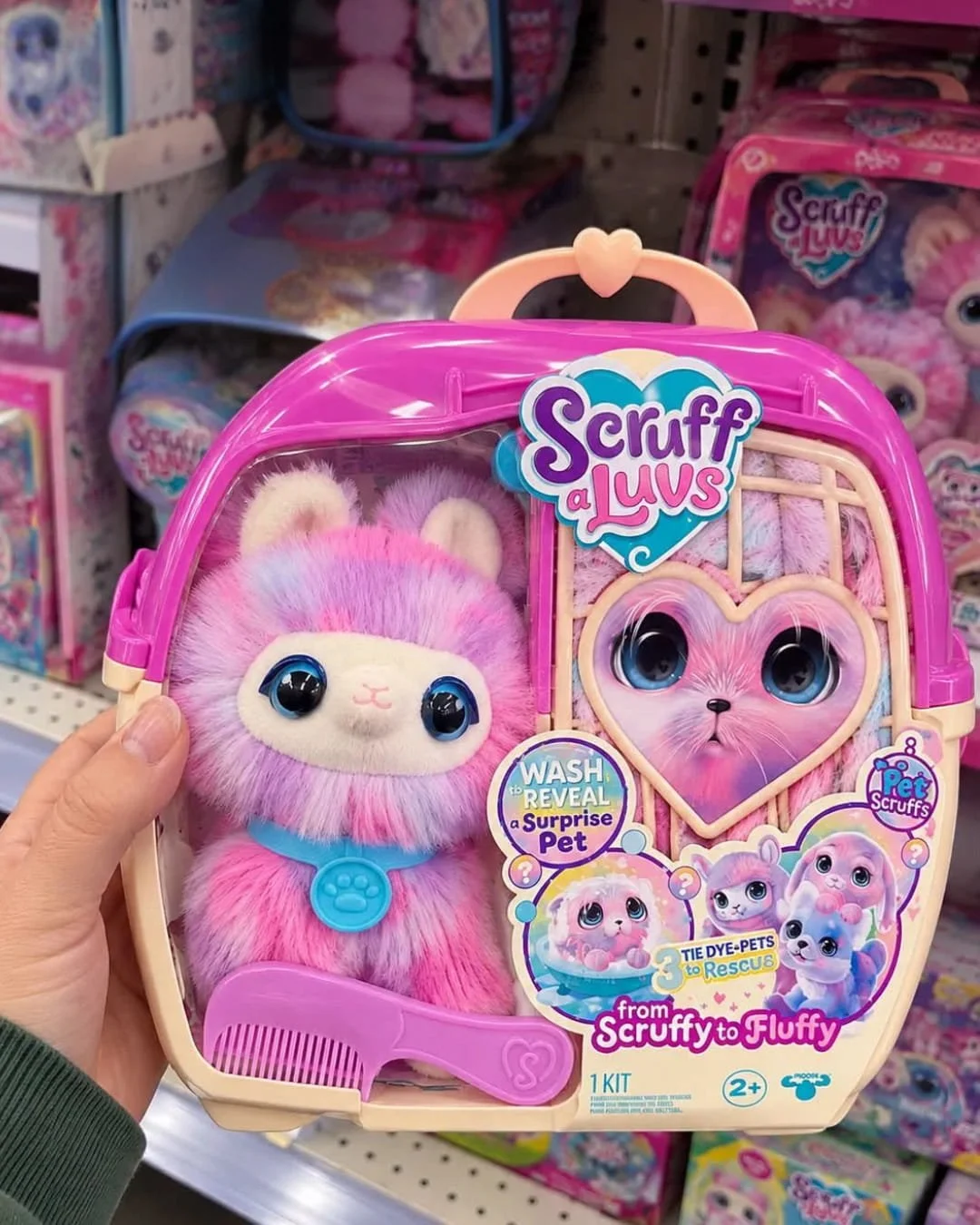 Hand holding Scruff a Luvs tie-dye mystery plush toy package with surprise pet reveal in a retail store aisle