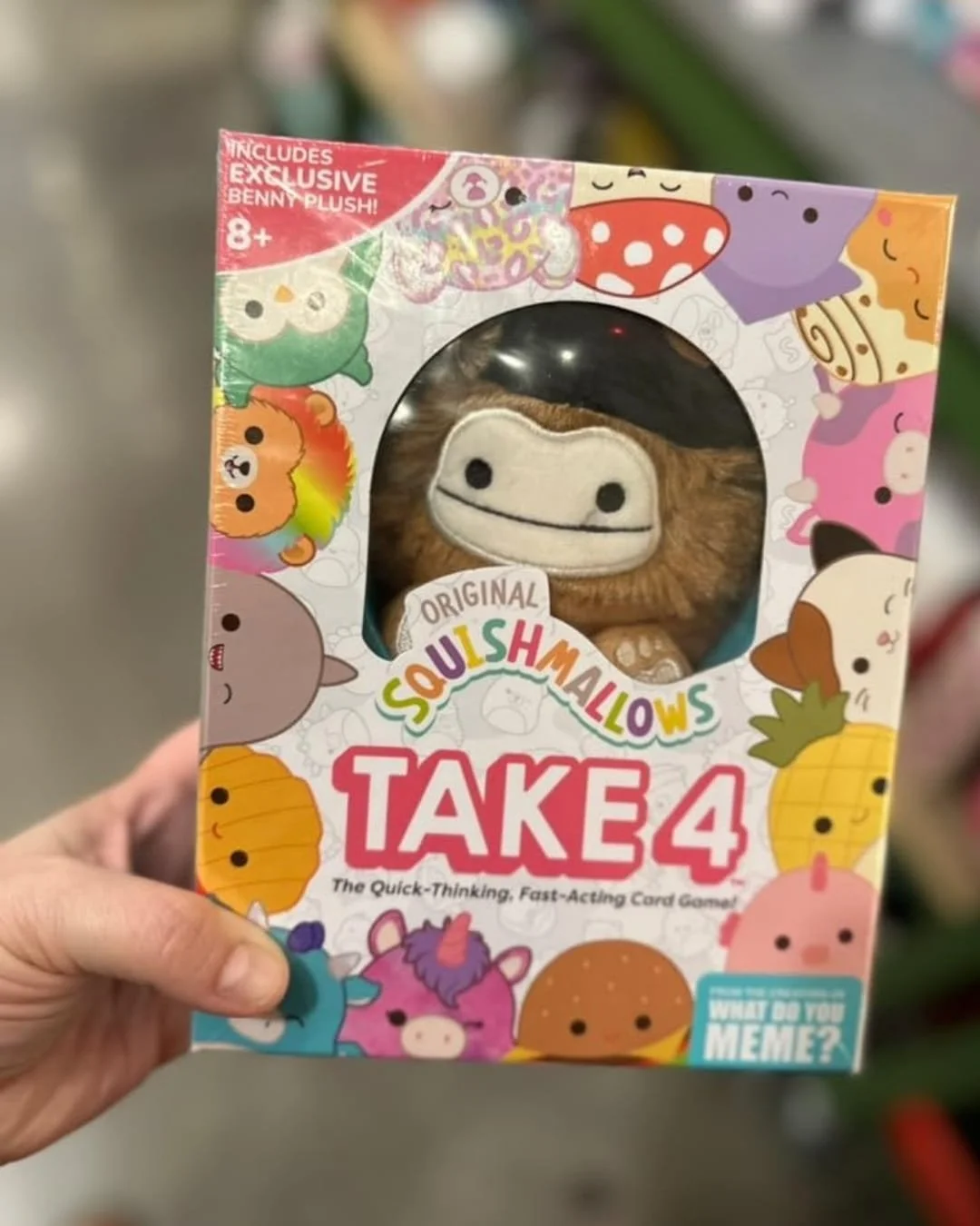 Retail box for Squishmallows Take 4 card game featuring colorful character illustrations and a central window displaying an exclusive Benny Bigfoot plush toy.