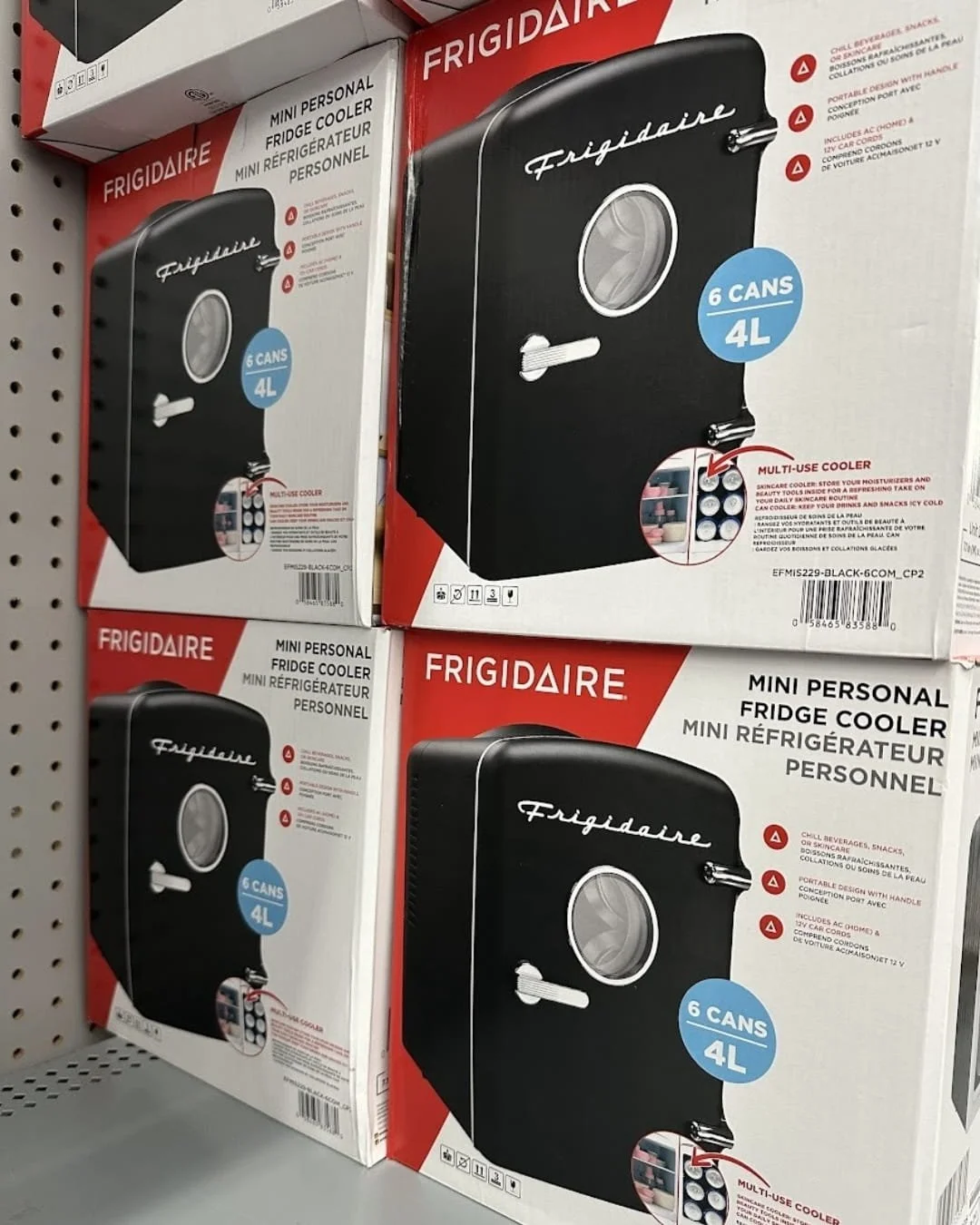 Stacked retail boxes of Frigidaire Mini Personal Fridge Cooler in black, featuring a retro design with a 6-can or 4L capacity, shown on a store shelf with bilingual English and French packaging.