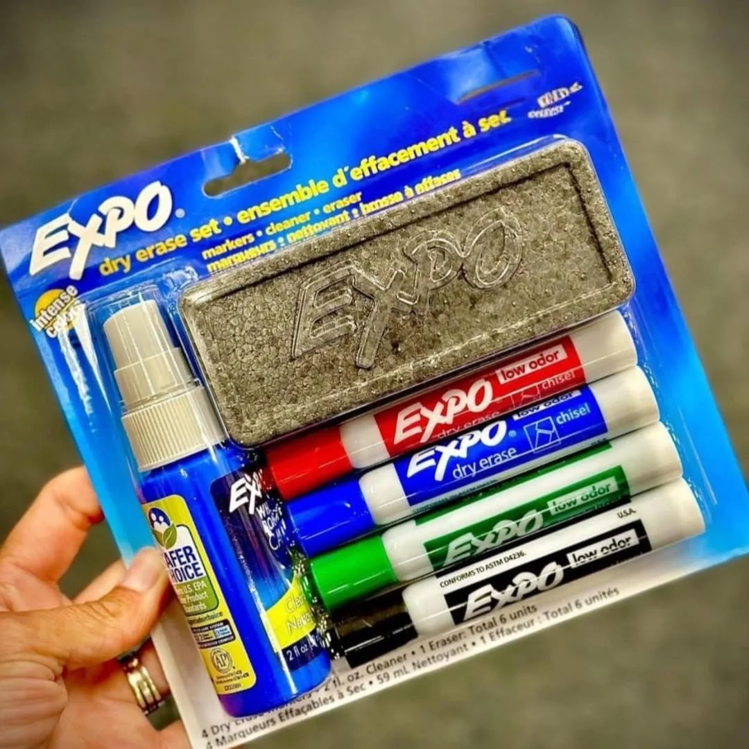 EXPO dry erase markers kit with four low-odor chisel-tip markers in red, blue, green, and black, a gray eraser, and a 2 fl oz EPA-certified dry erase cleaner, packaged in a clear blister pack.