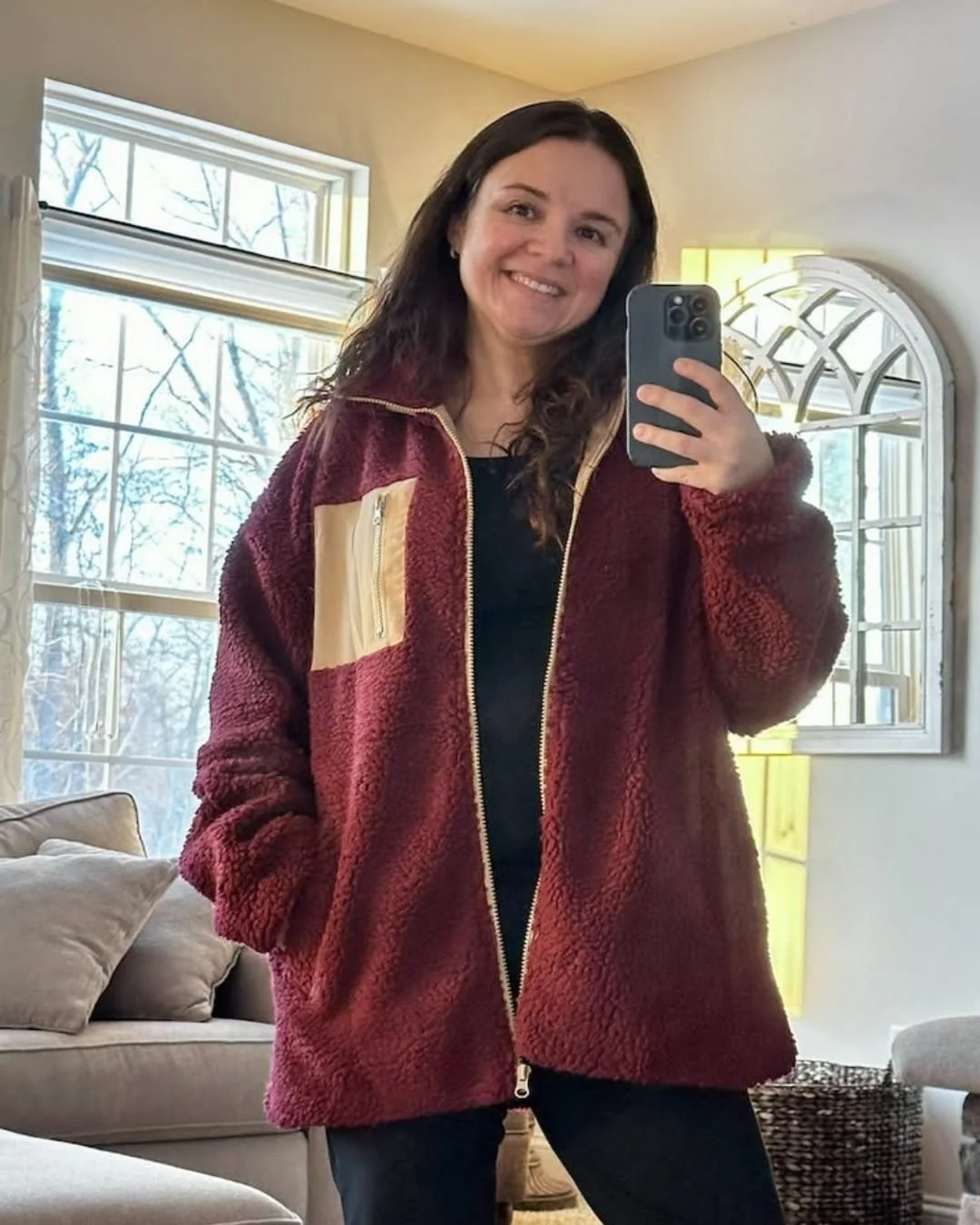 Nicole wearing a burgundy Dokotoo winter fleece jacket with a contrasting chest pocket in a cozy living room mirror selfie