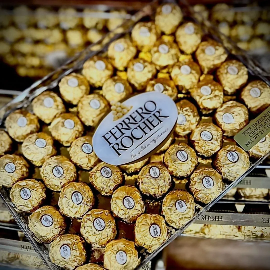 Ferrero Rocher gift box featuring gold-foil-wrapped hazelnut chocolates in a diamond-shaped transparent container, showcasing the luxurious and iconic presentation.