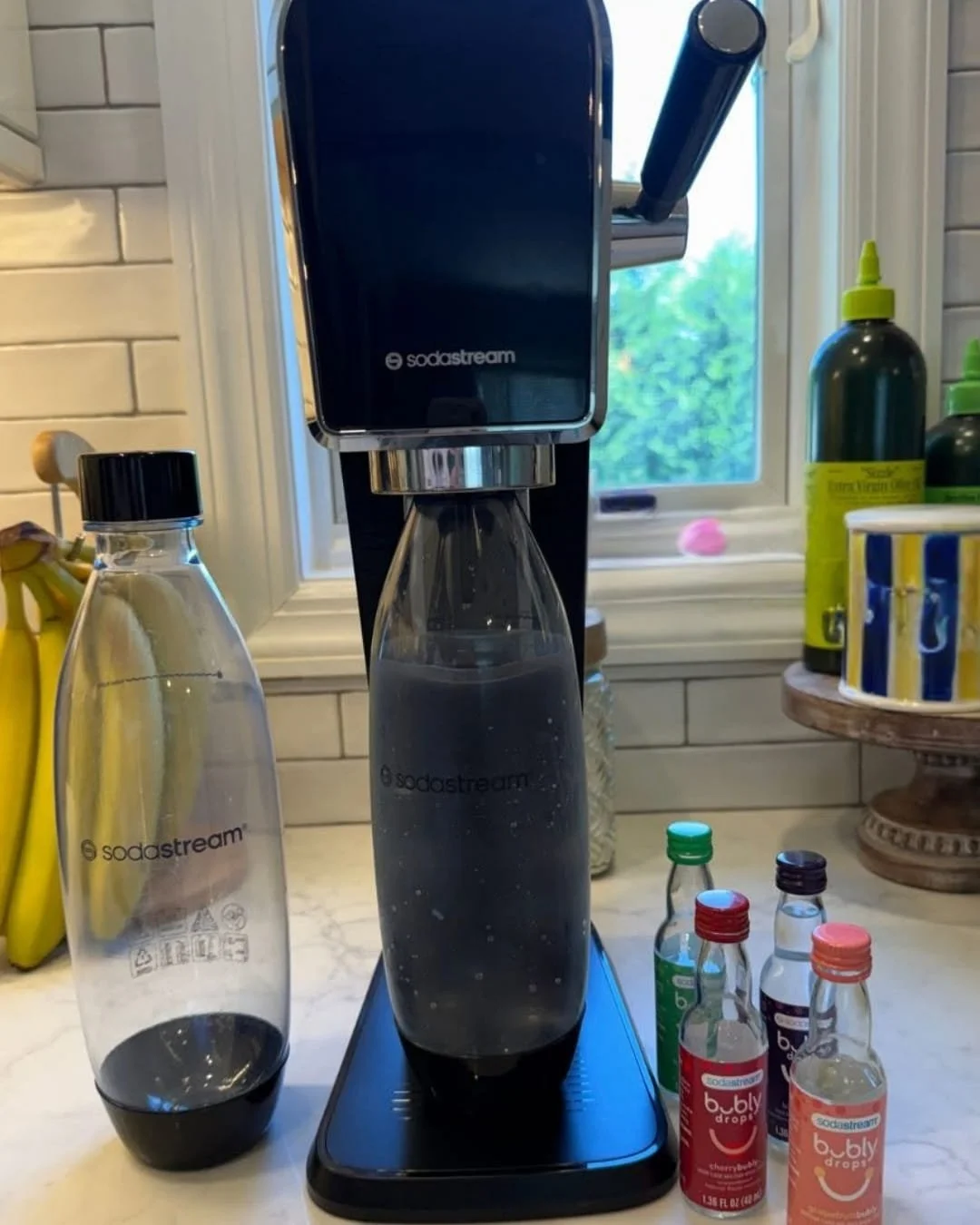 SodaStream sparkling water maker on a kitchen counter with carbonation bottles and flavored water drops nearby