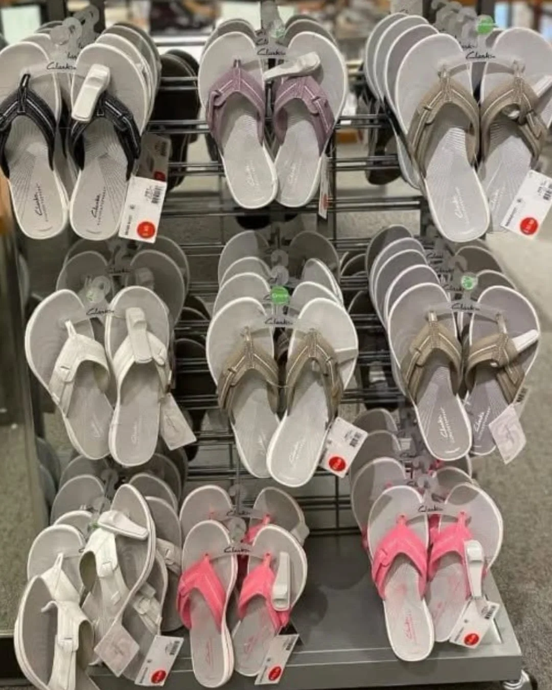 Retail display of Clarks women's flip-flop sandals in multiple colors with cushioned footbeds and clearance tags