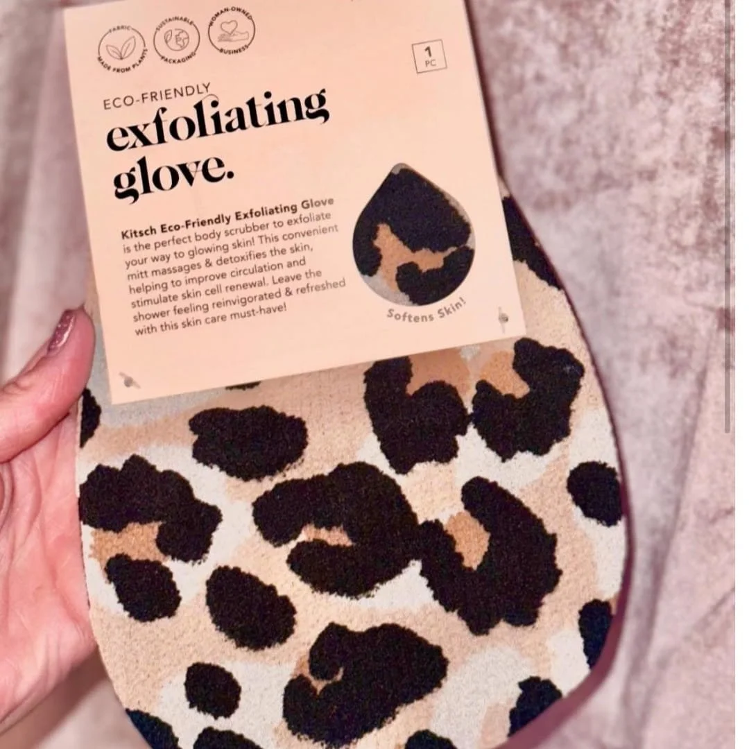 Kitsch eco-friendly exfoliating glove with leopard print design, featuring sustainable packaging and benefits like exfoliation, detoxification, and improved circulation, held by a hand with glittery nails.