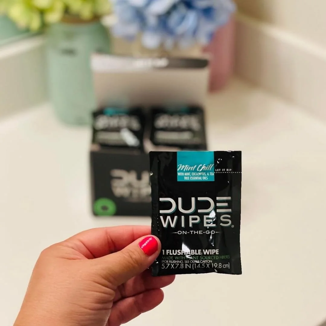 DUDE Travel Wipes Mint Chill single packet held in hand with product box in background