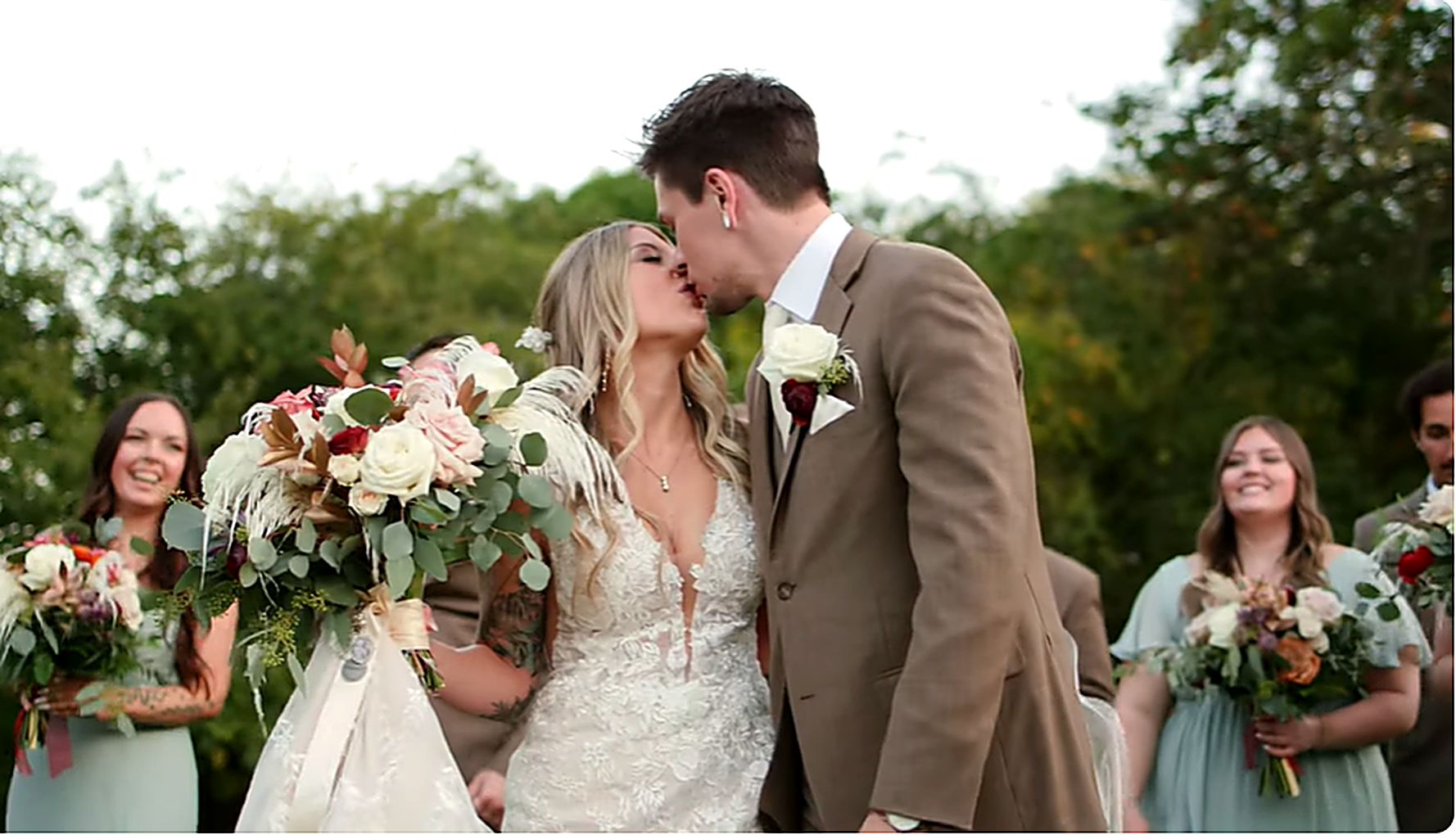Bride and groom kissing surrounded by wedding party