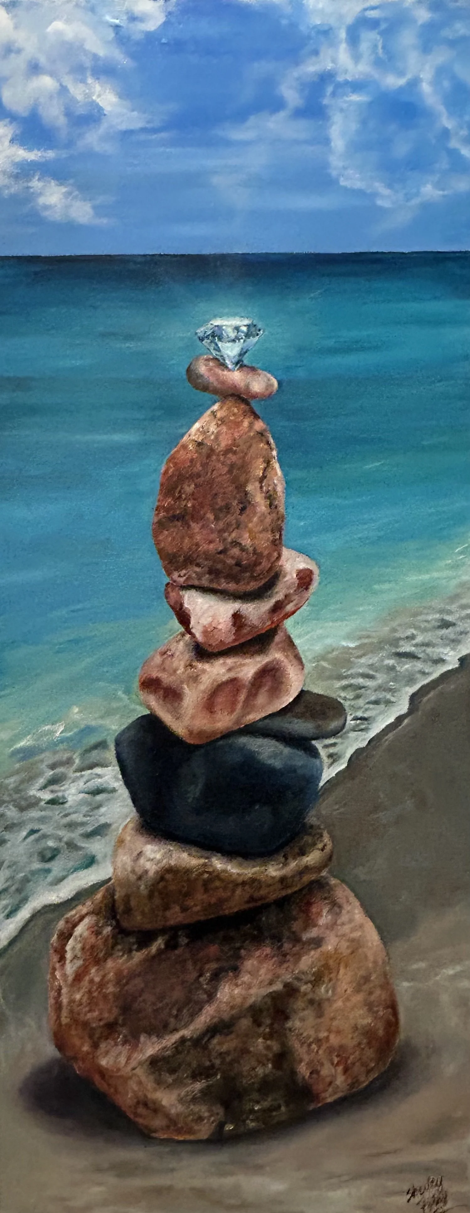 A stack of seven rocks of various sizes and colors, with a diamond on top, set on a beach with the ocean and blue sky in the background.