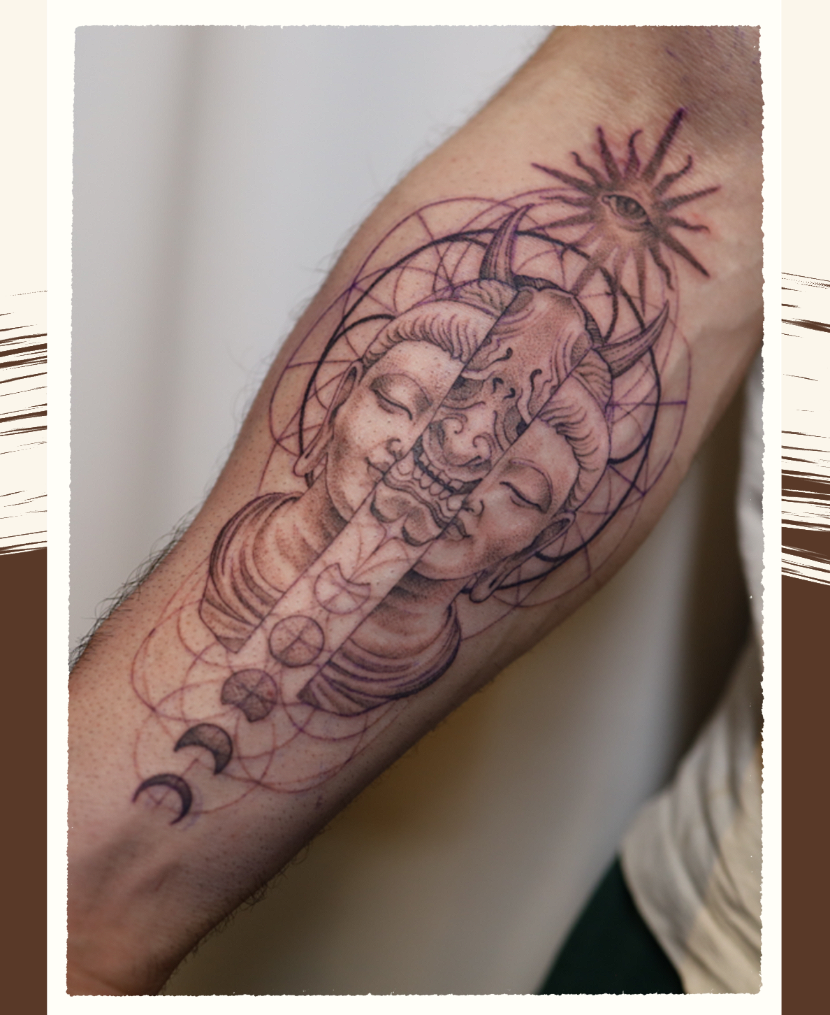 Tattoo of Buddha and a hanya mask skull with horns, and various celestial symbols including a star with an eye, on a person's forearm.