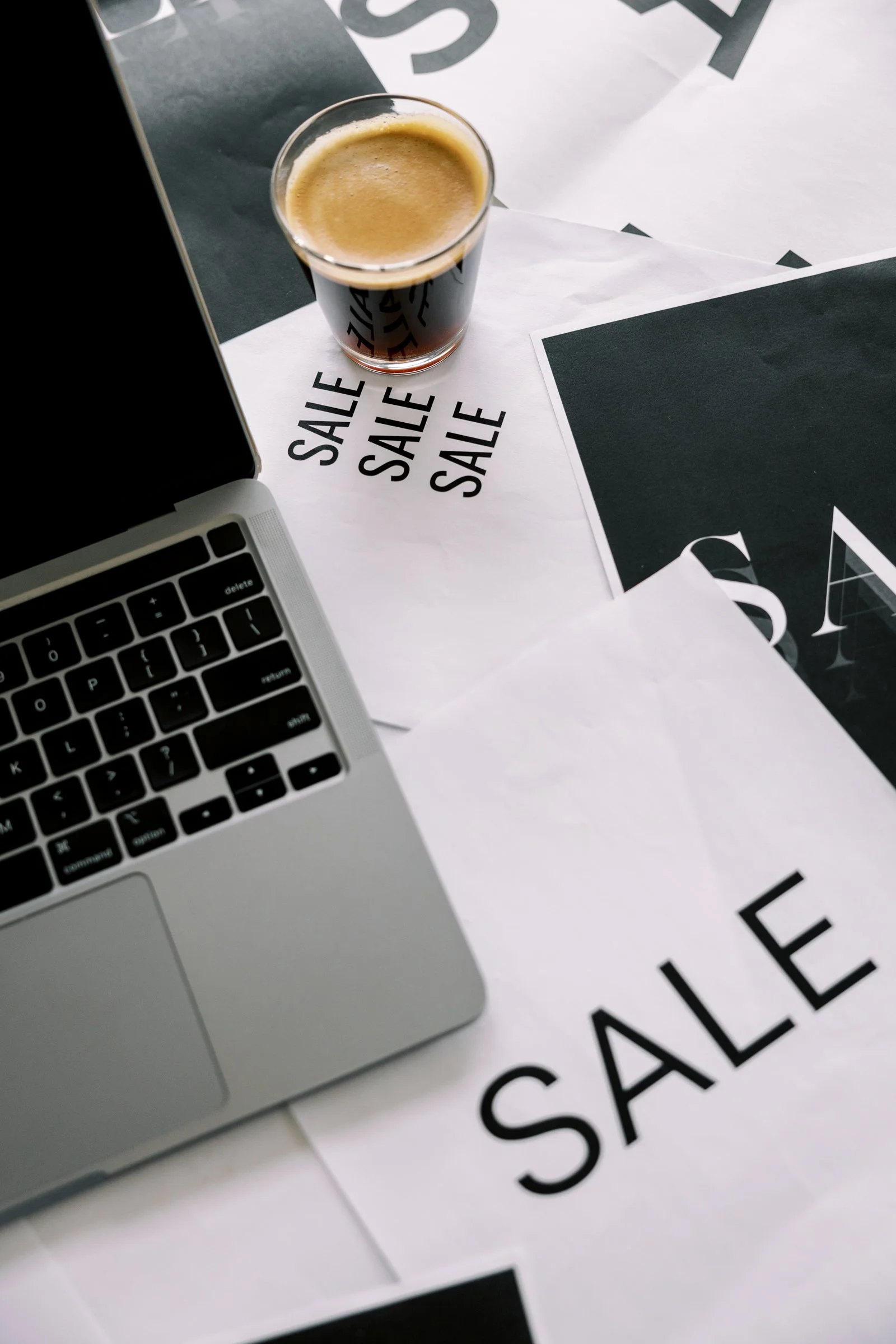 Laptop and coffee cup with Black Friday sale papers representing small business website design and marketing offers.