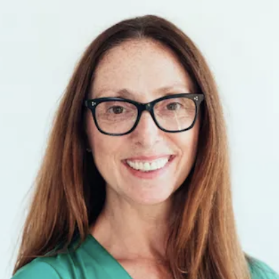 Portrait of a woman with long brown hair, wearing glasses and a green top, smiling at the camera.