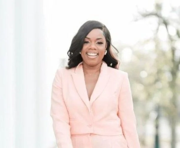 Woman in a light pink suit smiling outdoors