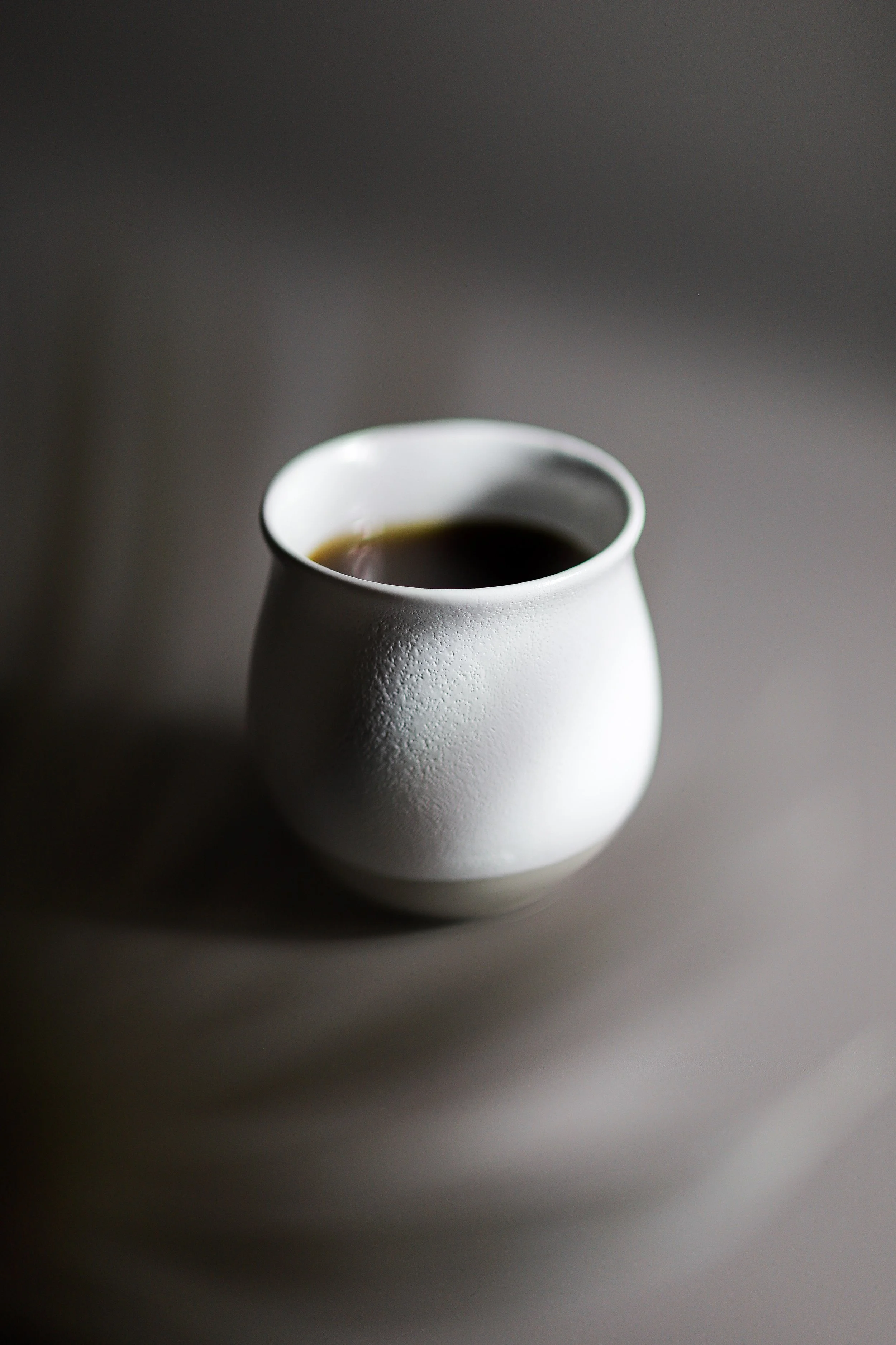 White ceramic cup with black coffee on neutral background