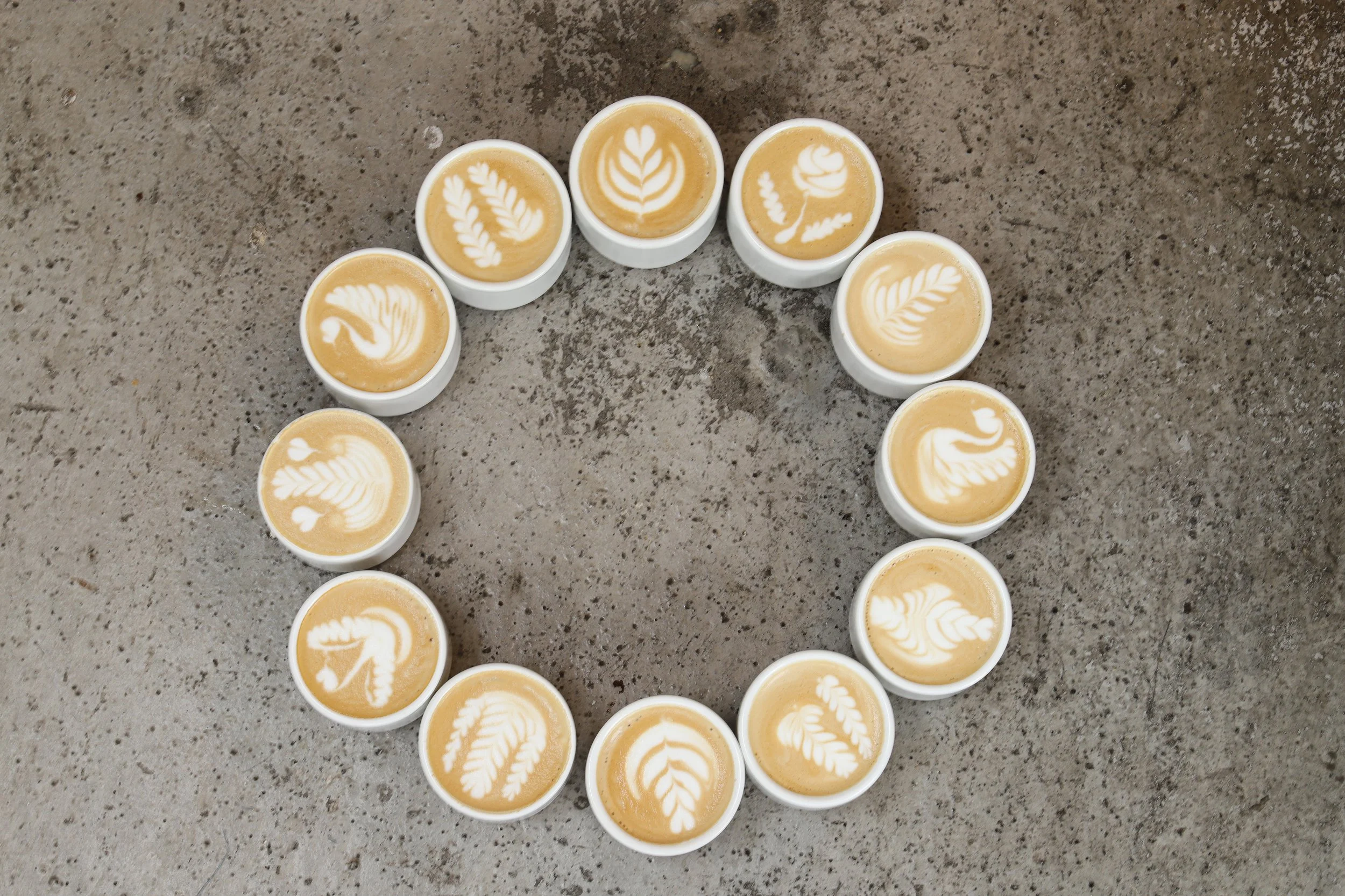 Circle of cappuccinos with latte art on gray surface