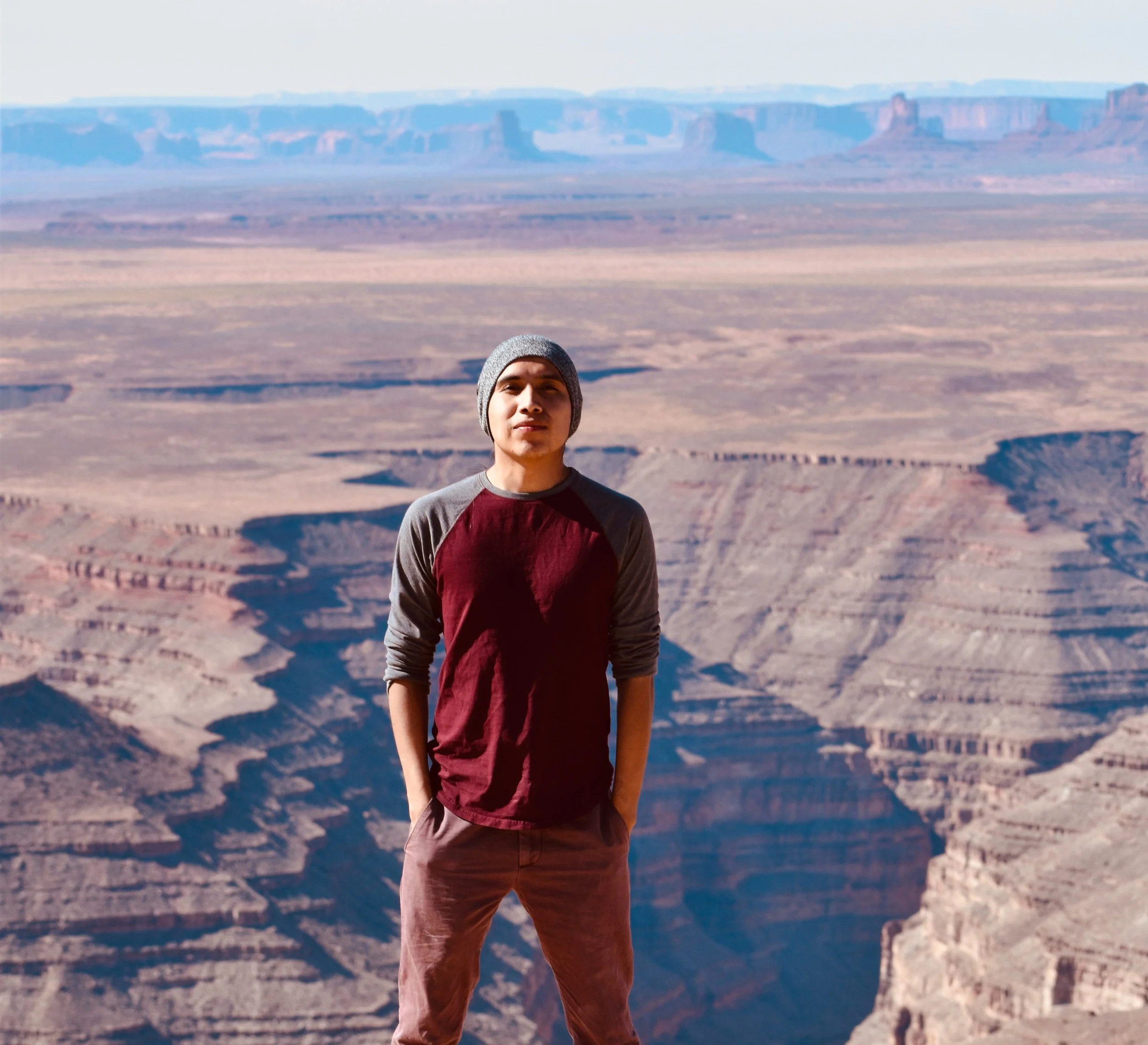 Young man standing at the Grand Canyon wearing a beanie and casual clothing.