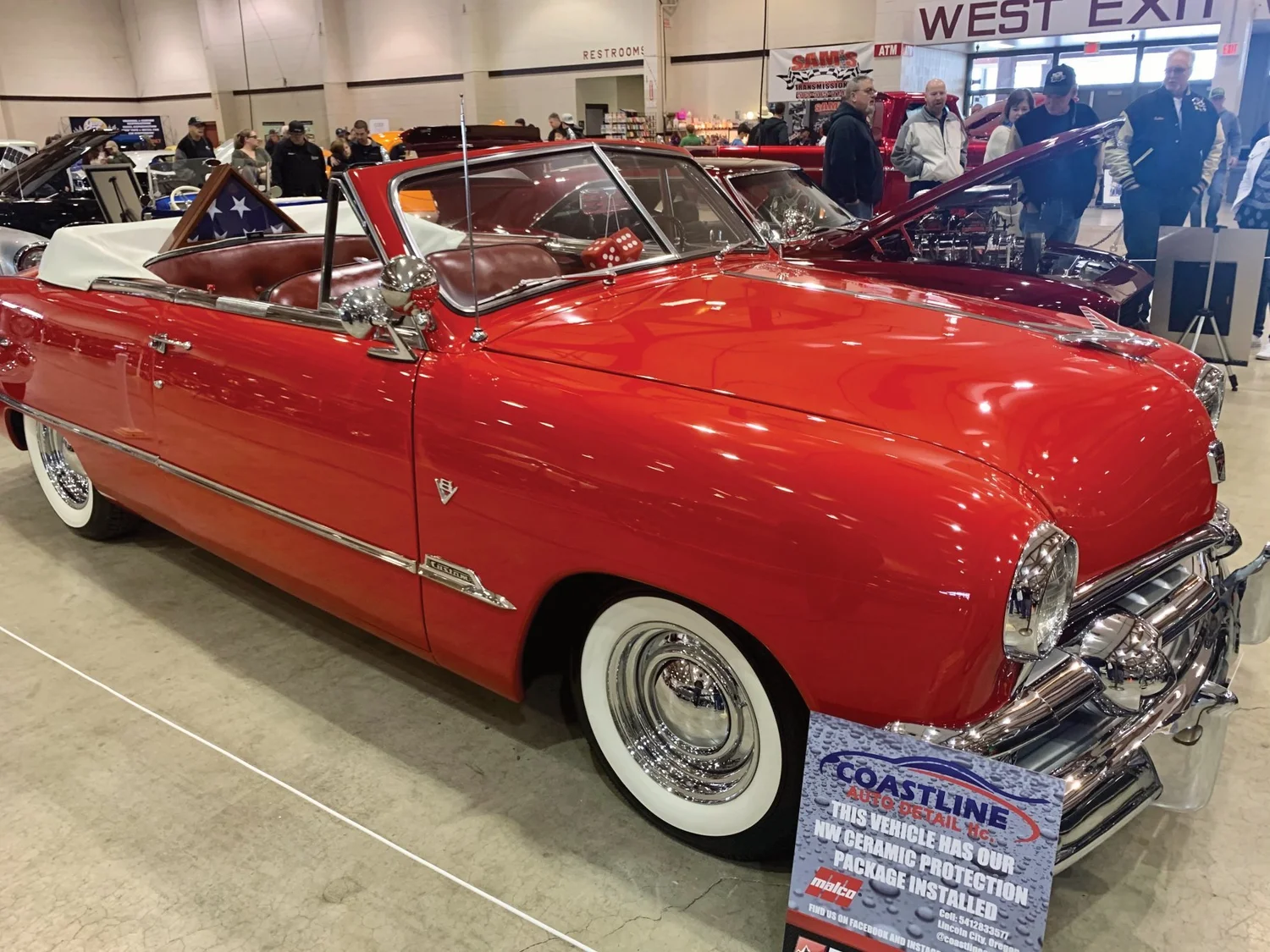 Classic red convertible displayed at a car show with Coastline Auto Detail ceramic protection signage