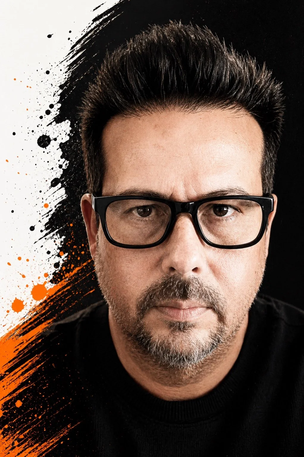 Close-up of a middle-aged man with dark hair, glasses, and a short beard, against a black background with orange and black paint splatters.
