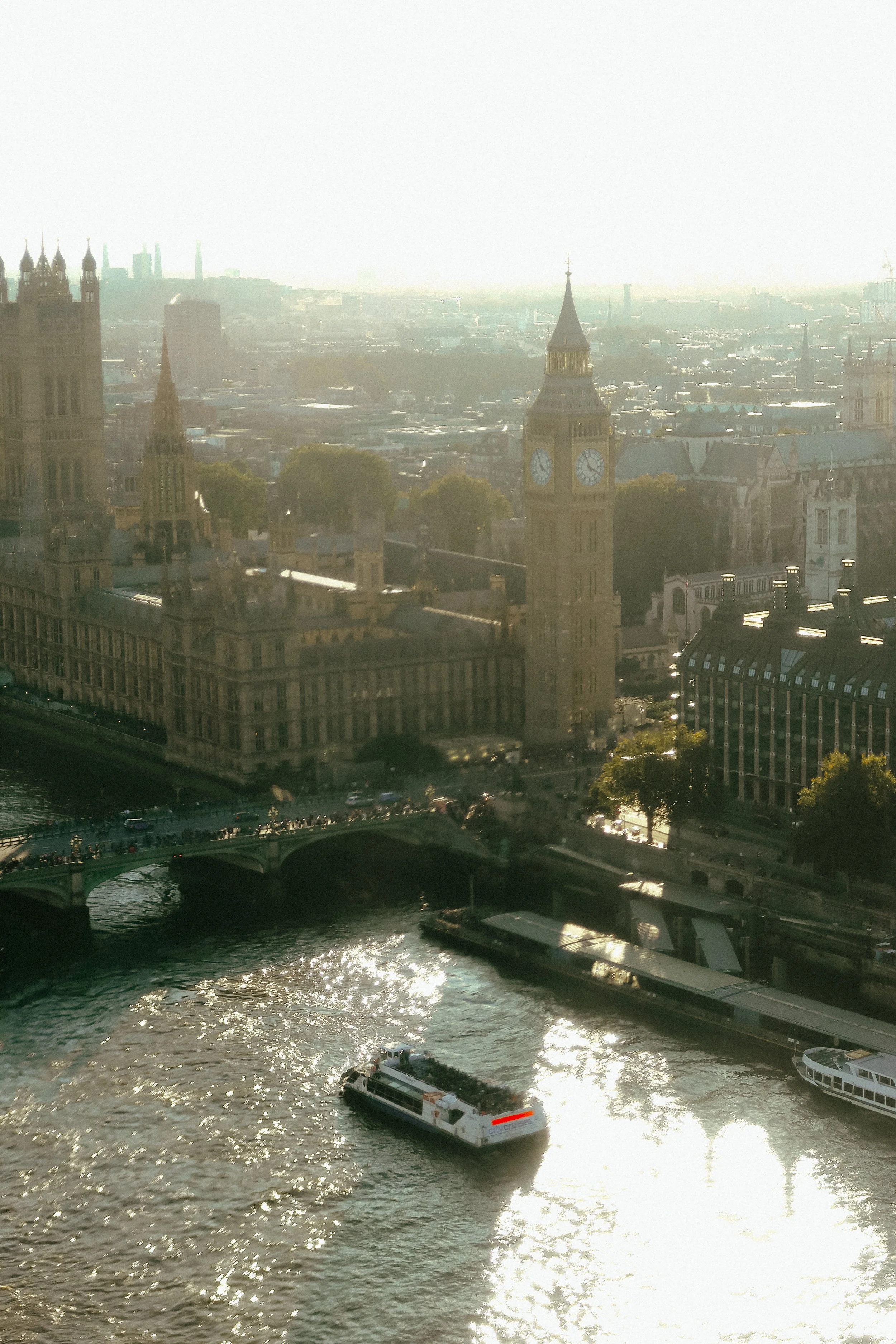 Aerial view of London with a boat on the river Thames, Big Ben clock tower, and the Palace of Westminster.