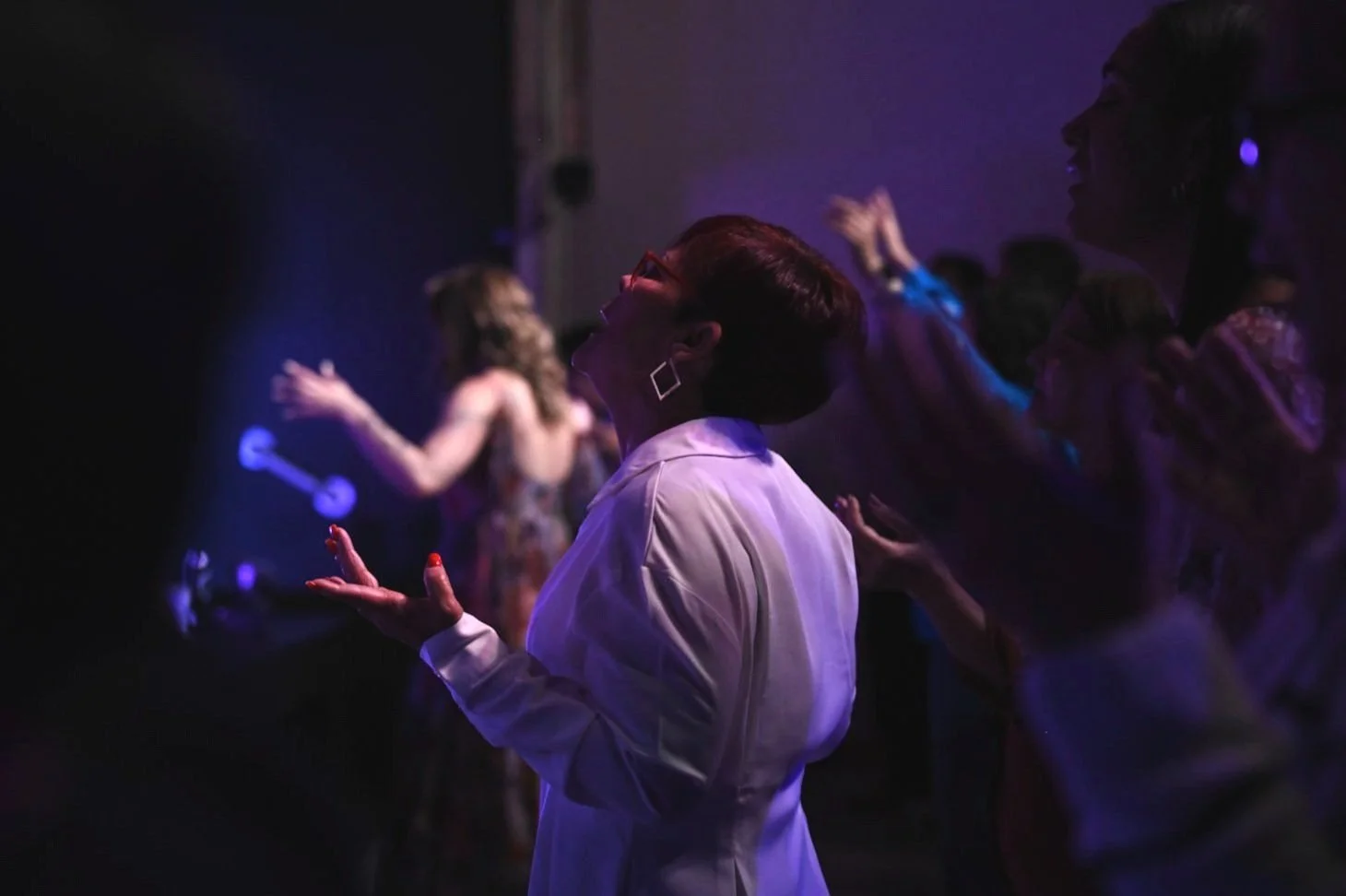 People dancing and praying in a dark, colorful room.