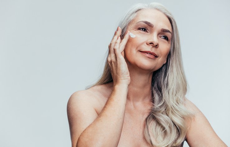 Woman applying moisturizer to mature skin, representing professional skincare, hydration, and barrier support.