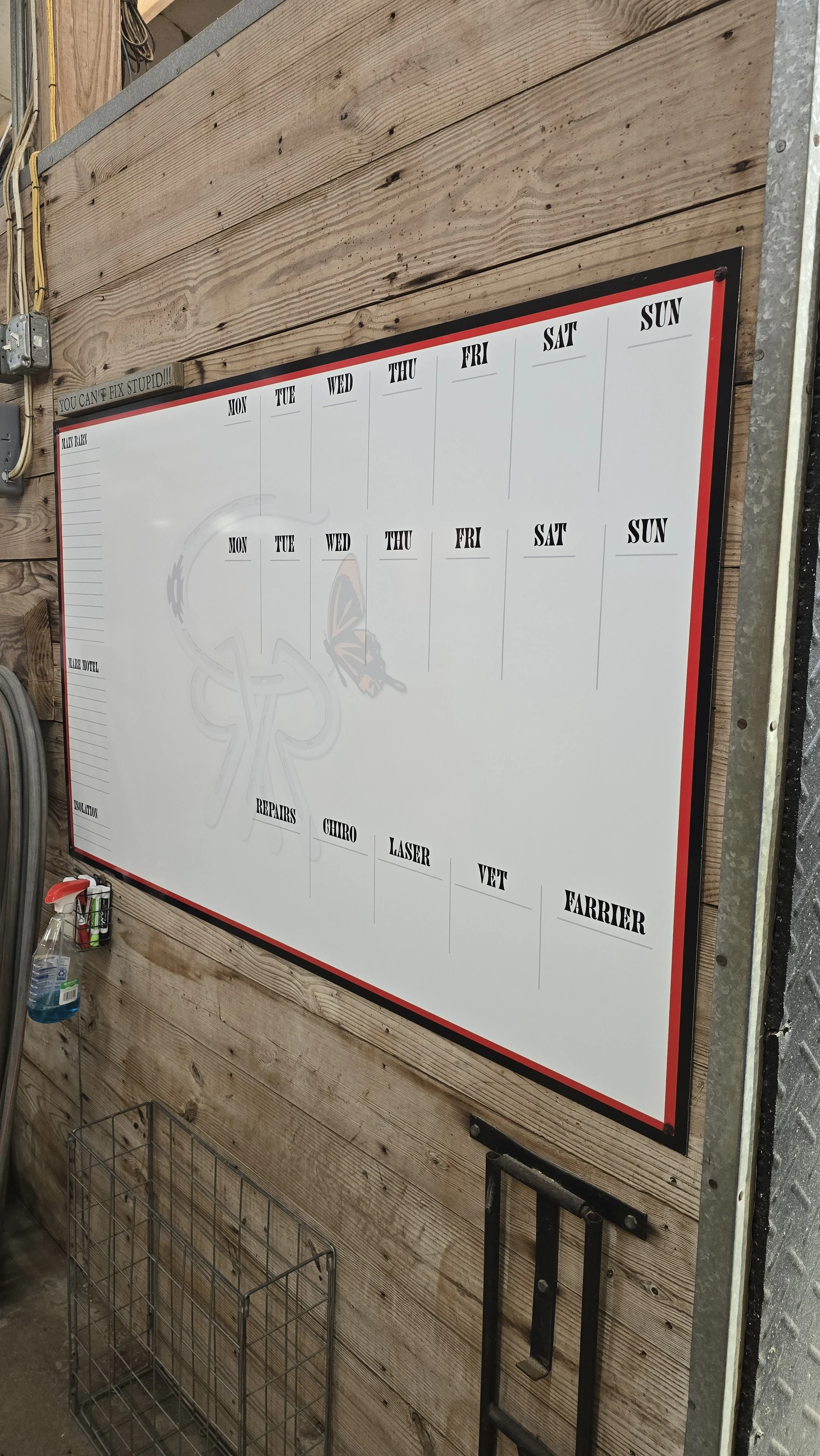 Whiteboard with weekly schedule and list of services like repairs, chiro, laser, vet, and farrier, mounted on a wooden wall in a workshop or garage.