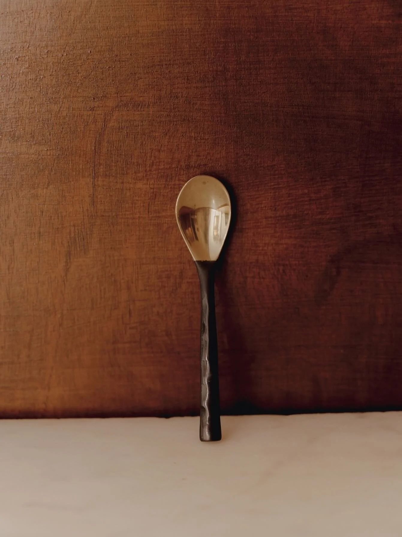 *

A small brass spoon for everyday moments.

Solid brass, crafted in Indonesia by skilled metal artisans.

Its dark antique finish will soften over time, developing a natural patina &mdash; each mark becoming part of its story.

Simple. Weighty. Mad