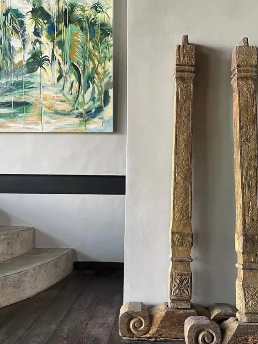 *

Two carved wooden columns, once part of a traditional piece, now placed against the wall.

A painting by the owner, @yoginikamadevi,
and a wooden beam cutting across the space &mdash; lines, textures, and architectural elements coming together nat
