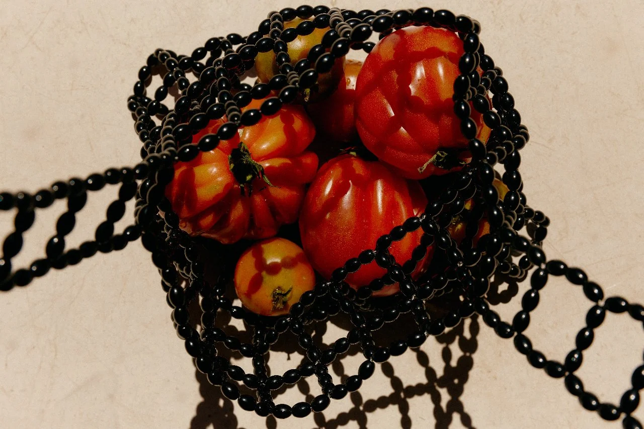 Heirloom tomatoes styled in a sculptural black net for a Feast with Fiore private chef experience in Los Angeles.