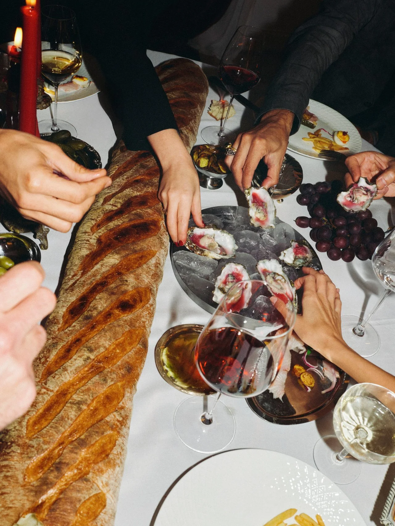 Guests sharing bread, oysters and wine around a Feast with Fiore dinner table in Los Angeles.