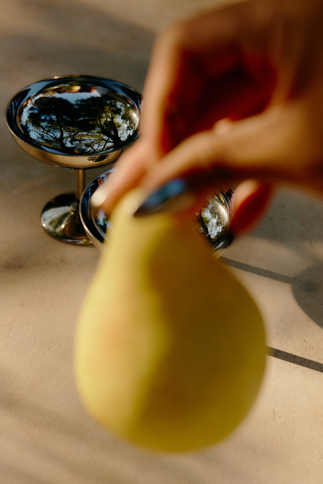 Hand serving a fresh pear beside a cocktail glass for a Feast with Fiore event bar experience in Los Angeles.