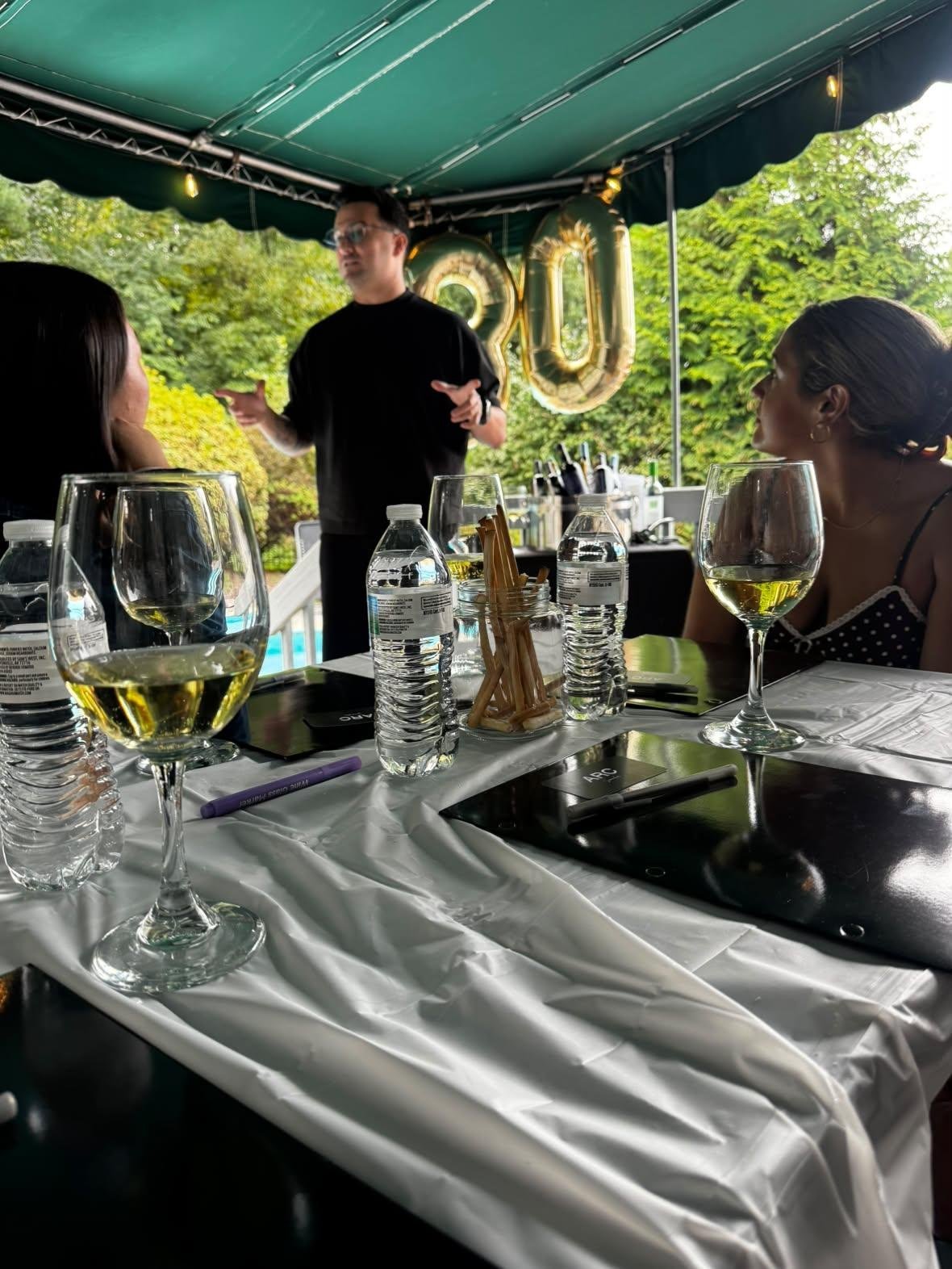 Angel presenting at a wine tasting under a tent with '30' balloons