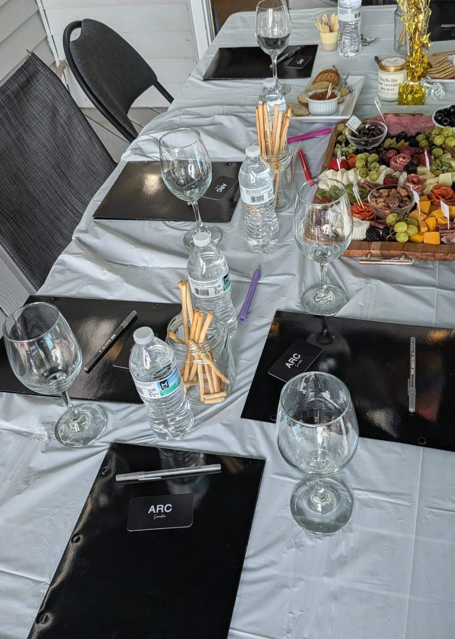 Private wine tasting table setup with ARC-branded clipboards, wine glasses, and charcuterie board
