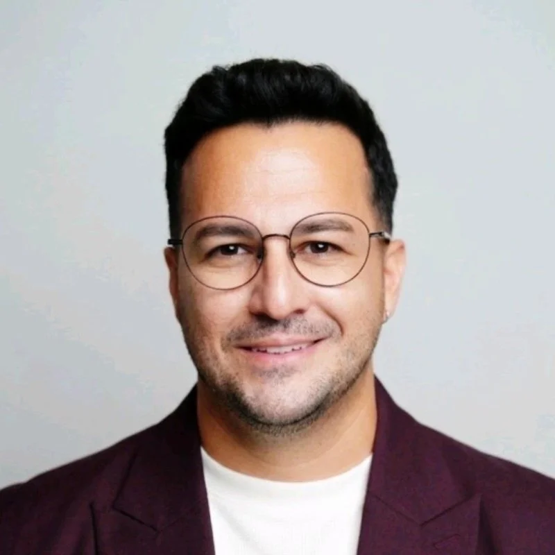 Portrait of sommelier Angel Ramón Crespo smiling, wearing glasses and a maroon blazer