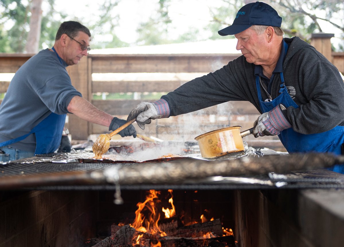  Jim Grenz (right) lathers an oil mixture onto salmon filets on April 7 at the Kiwanis Salmon Barbecue at Hillcrest Park in Mount Vernon. The annual fundraiser serves salmon meals every Friday, Saturday and Sunday in April. 