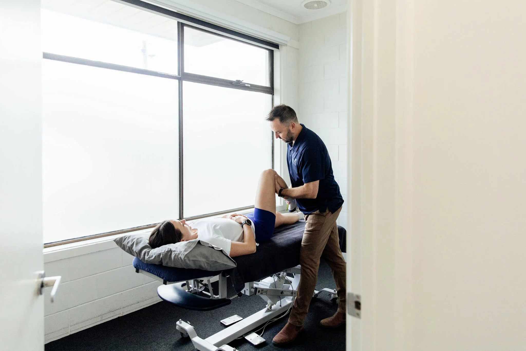Osteopath assessing a patient's hip and knee on the treatment table at OGOSH