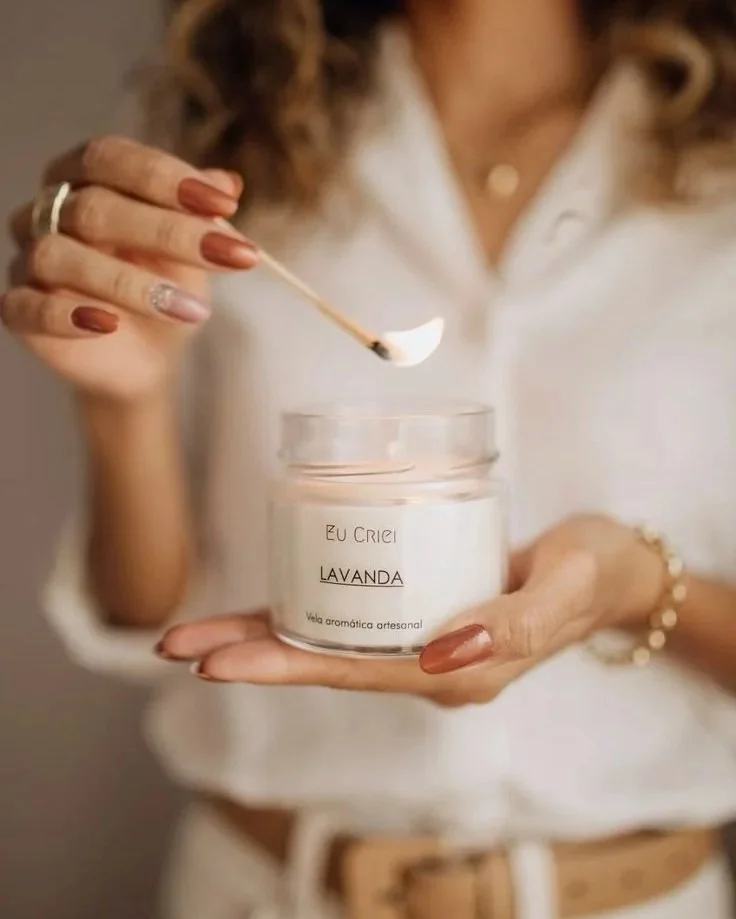 Donna che tiene una candela aromatica alla lavanda, usando uno stecchino per accenderla.