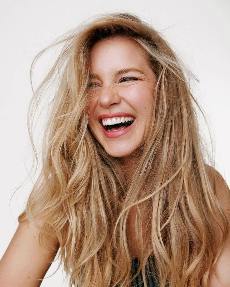 Ragazza sorridente con lunghi capelli biondi e ondulati