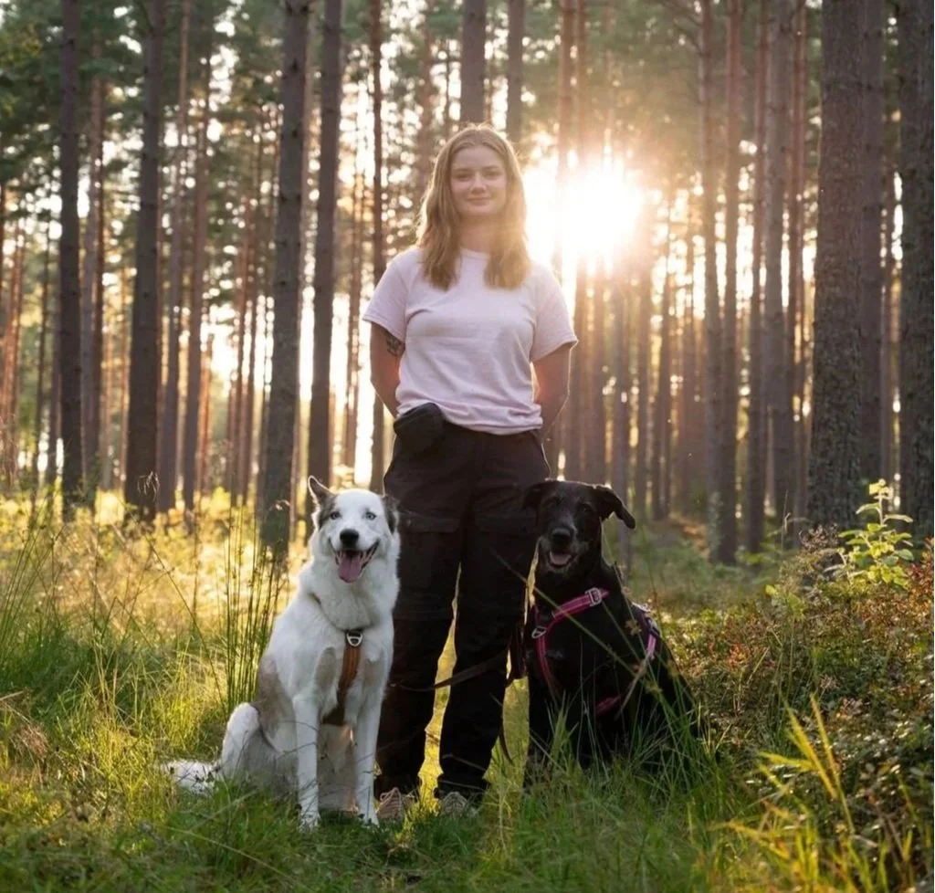 Hundtränare Ulrika Winge med två hundar i skogen