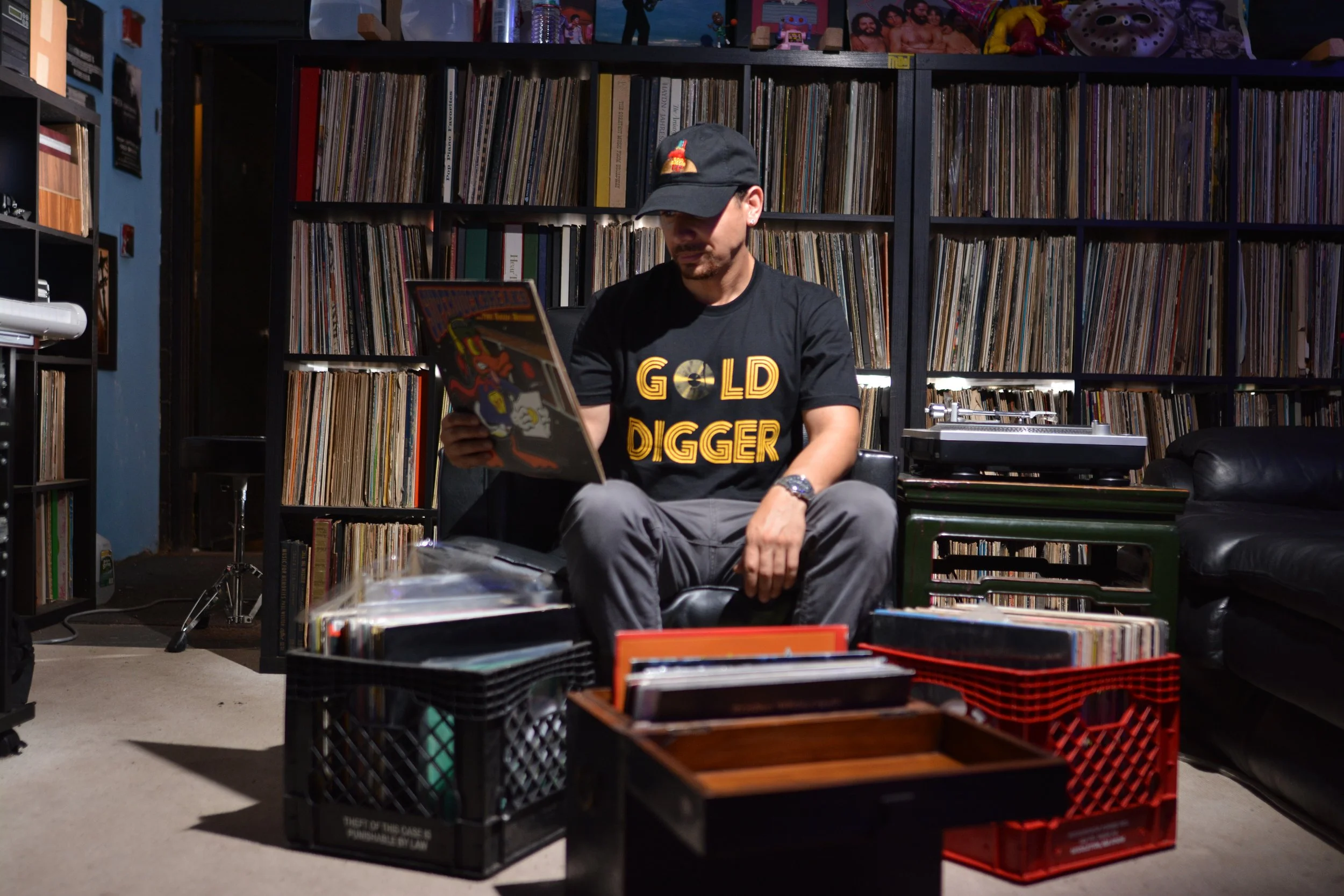 A man wearing a black baseball cap and a black T-shirt with gold