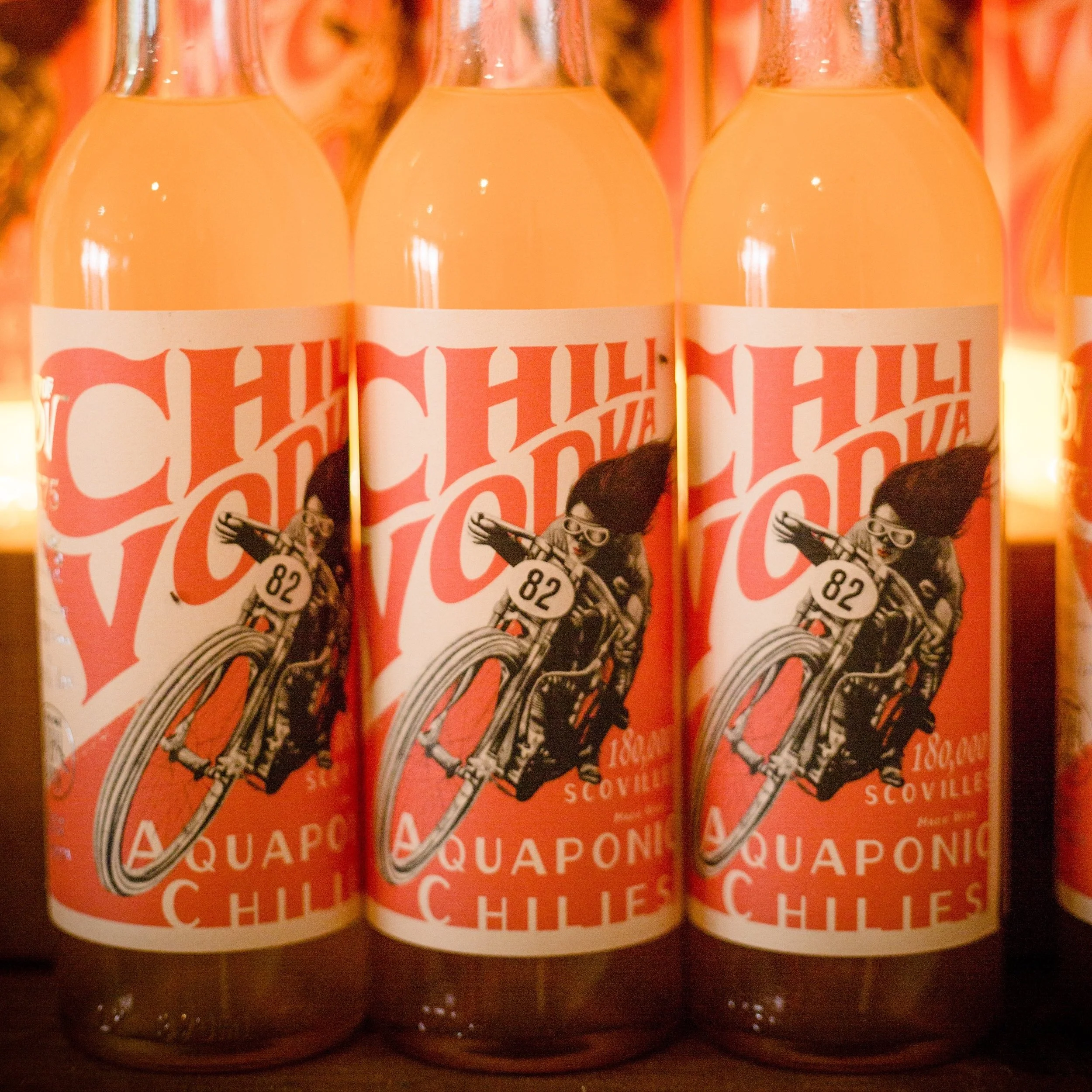 Bottles of chili vodka with a vintage-style label featuring a woman riding a motorcycle and bold red text.