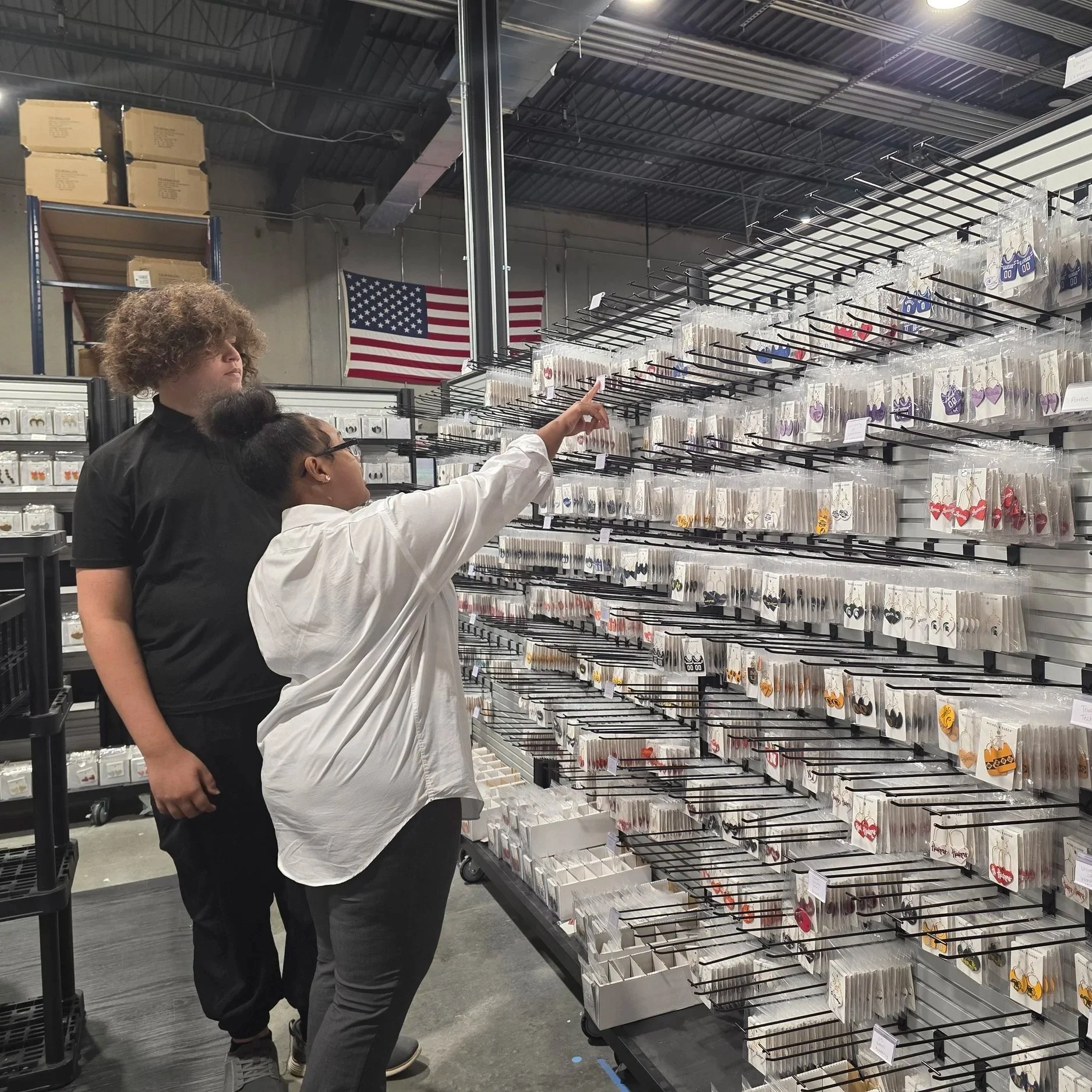 Two students examine a jewelry display wall during an industry site visit.