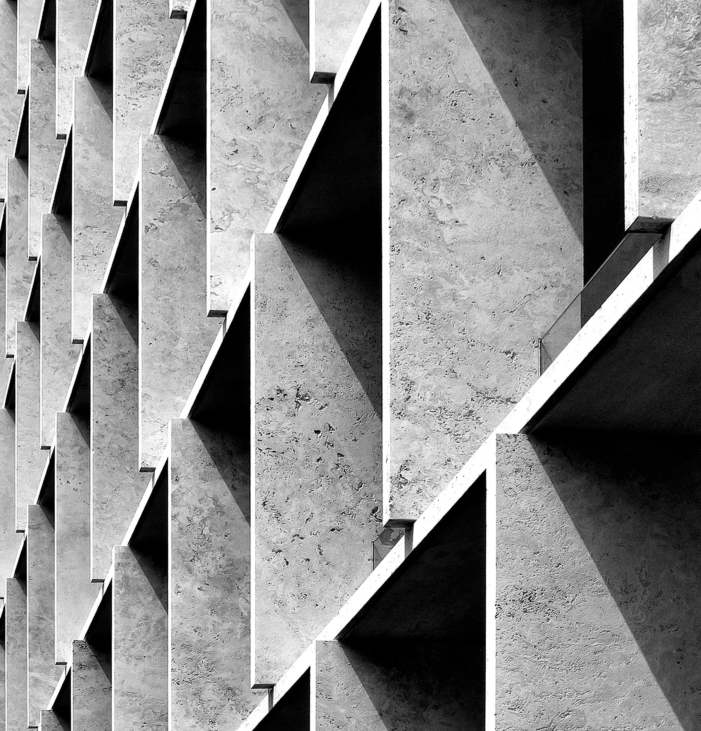 Close-up of a modern concrete building facade with repetitive square indentations creating shadows.