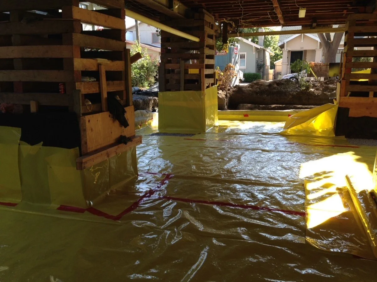 Interior of a house under construction with wooden framework and yellow waterproofing material on the floor and walls